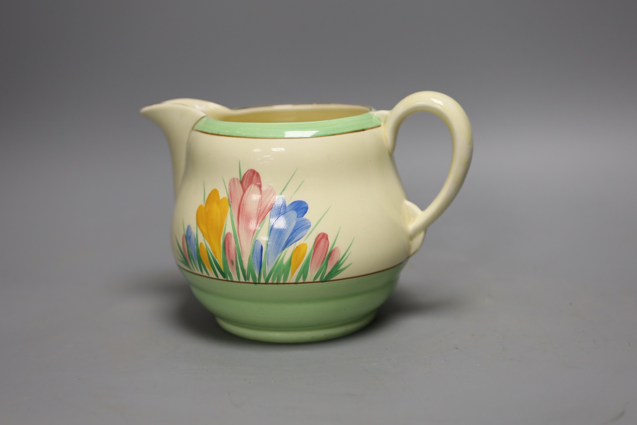 A Clarice Cliff crocus design milk jug and a Bizarre patterned side plate, jug 11.5 cms high